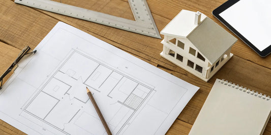 House plans and blueprints on a desk with a model home, used for planning a new build.